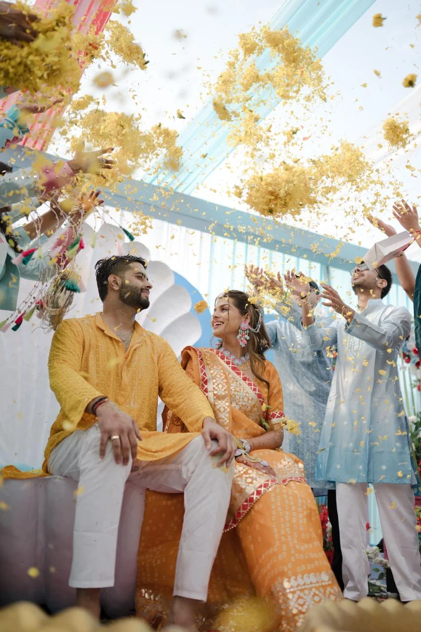 Couple during a haldi celebration with petals falling